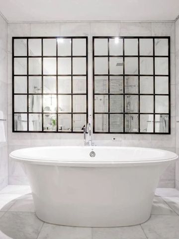 Luxuriöses Badezimmer mit freistehender Badewanne und großen Spiegeln