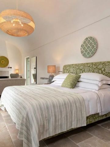 Elegantes Schlafzimmer mit grünem Kopfteil und großen Fenstern im Hotel
