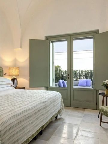 Schlafzimmer mit Doppelbett und Blick auf eine grüne Terrasse durch geöffnete Fenster