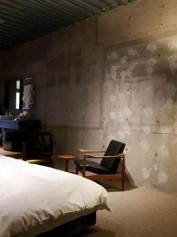 Industrielles Designzimmer mit freiliegender Betonwand und gemütlichem Bett