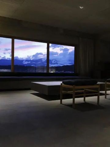Gemütlicher Raum mit Panoramafenster und Blick auf die Berge in der Dämmerung