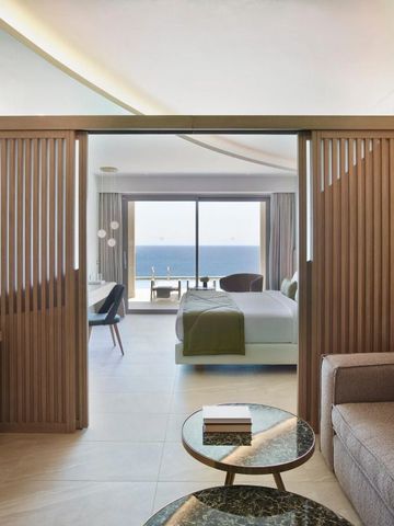 Geräumige Suite mit Holzdetails und Meerblick durch offene Fensterfront