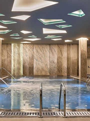 Design-Innenpool mit markanter Deckenbeleuchtung und Marmorwänden im Wellnessbereich
