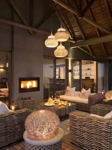 Beleuchtete Lounge mit Kamin und Korbmöbeln auf einer Terrasse