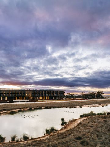 Das lang gestreckte Resortgebäude hinter einer Wasserstelle in der offenen Graslandschaft