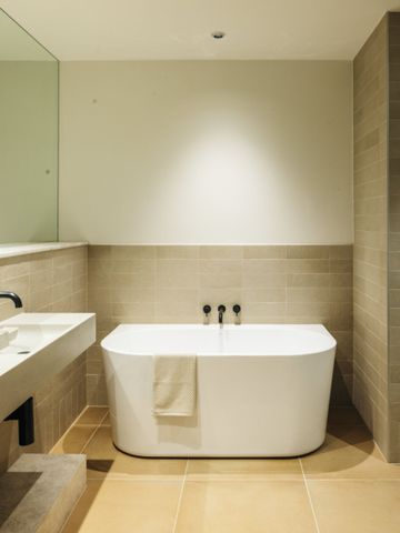 Bad mit freistehender Badewanne, langem Waschtisch und hellen Fliesen