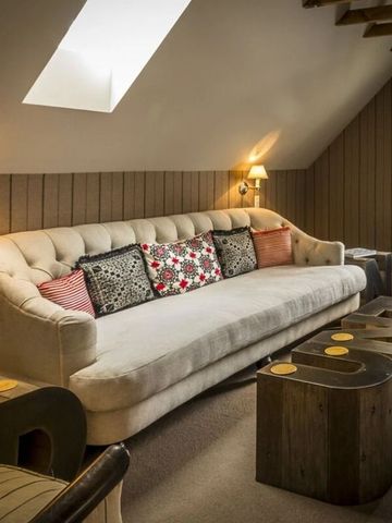 Wohnzimmer mit stilvollem Sofa und rustikalen Tischen unter Dachschräge