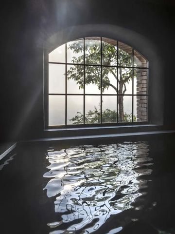 Innenpool mit großem Fenster, das auf Baum und Landschaft blickt