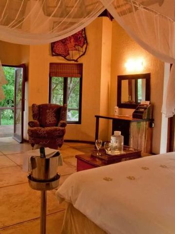 Luxuriöses Schlafzimmer mit Blick auf die Natur, Sitzbereich und Himmelbett.