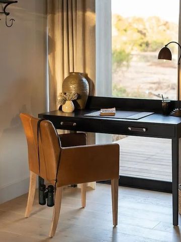 Arbeitsbereich mit Schreibtisch und elegantem Holzstuhl, Blick nach draußen.
