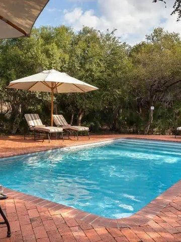Klarer Pool mit Sonnenschirmen und Liegestühlen im Grünen