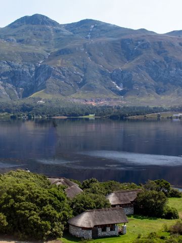 Weite Landschaft mit See und umliegenden Bergen sowie traditionellen Lodges