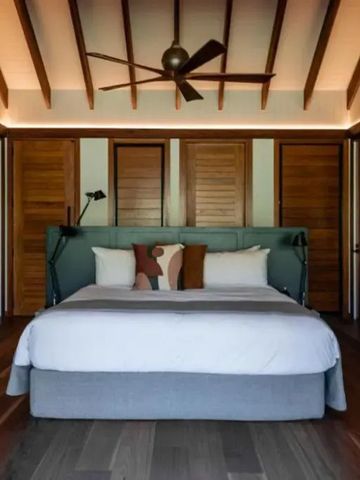 Elegantes Schlafzimmer im Hotel mit Holzverkleidung und Deckenventilator