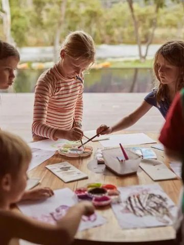 Kinder malen an einem Tisch mit Poolblick und Naturkulisse