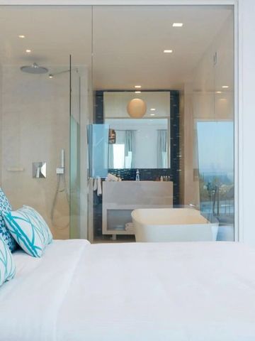 Komfortables Bett mit blauen Kissen und Blick ins Badezimmer mit Glaswand