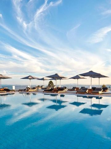 Sonnenschirme und Liegen am Pool mit klarblauem Himmel und Meer im Hintergrund