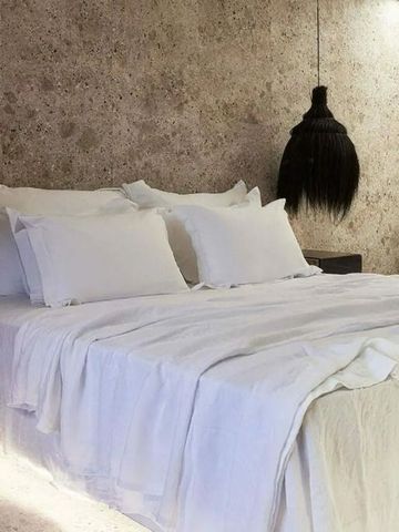 Gemütliches Bett in einem Hotelzimmer mit natürlichem Wanddesign