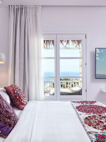 Lichtdurchflutetes Schlafzimmer mit Meerblick und bunten Kissen