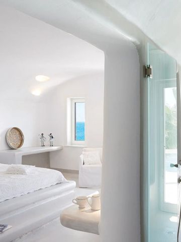 Geräumiges Zimmer in weiß mit Meerblick und minimalistischen Dekorationsobjekten.