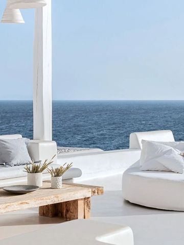 Elegante Terrasse mit Meerblick und gemütlichen weißen Sitzgelegenheiten.