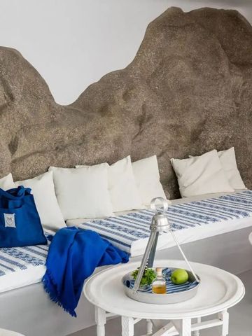 Sitzecke mit weiß-blauen Kissen und rustikaler Steinwand als Akzent.