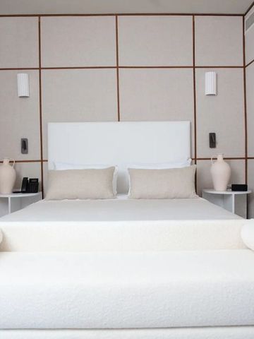 Minimalistisch eingerichtetes Hotelzimmer mit einem weißen Bett und heller Dekoration