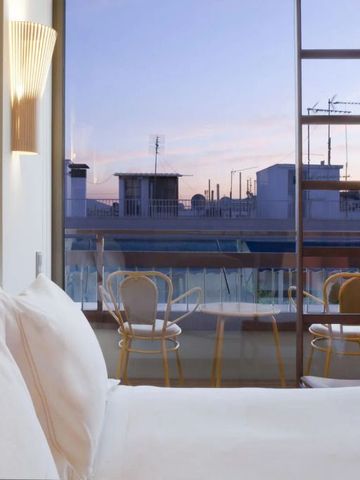 Geräumiges Zimmer mit großem Fenster und Blick auf Balkon bei Sonnenuntergang.
