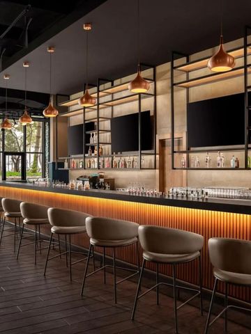 Elegante Bar mit Hockern aus Leder und moderner Beleuchtung