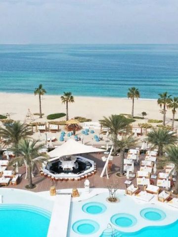 Überblick über den Pool und den Strand mit Palmen und türkisfarbenem Meer