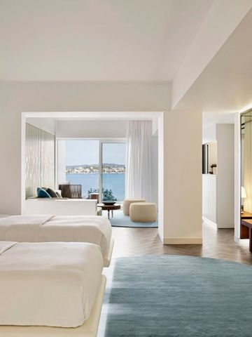 Helles Hotelzimmer mit zwei Betten und Blick auf das Meer