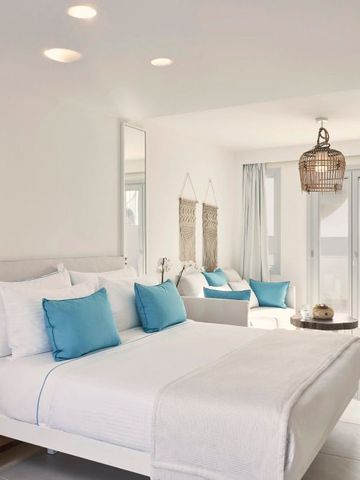 Luxuriöses, lichtdurchflutetes Zimmer mit großem Bett und gemütlicher Sitzecke.