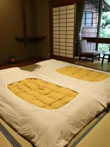 Japanisches Zimmer mit Futonbetten und Shōji-Schiebetür mit Blick in die Natur
