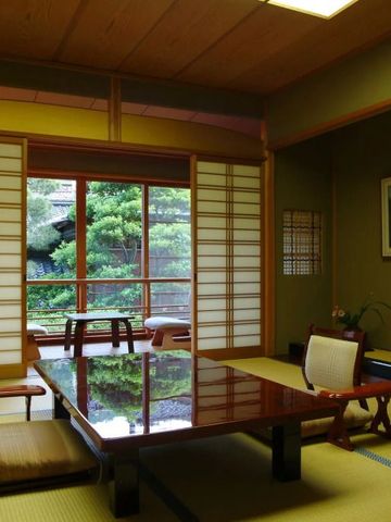 Traditionelles japanisches Zimmer mit Tatami und großem Holztisch, Blick auf Garten.
