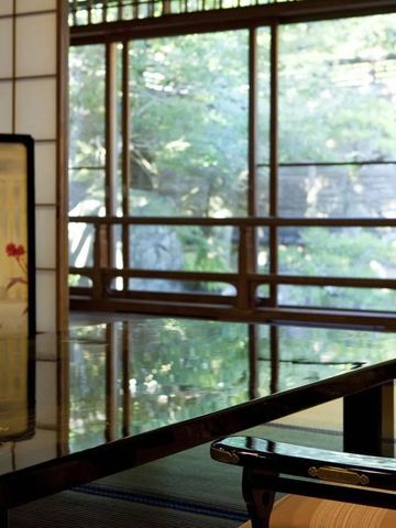 Detail eines japanischen Zimmers mit Paravent und Blick auf grünen Außenbereich.