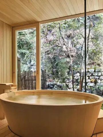 Holzverkleidetes Badezimmer mit runder Wanne und Naturblick.