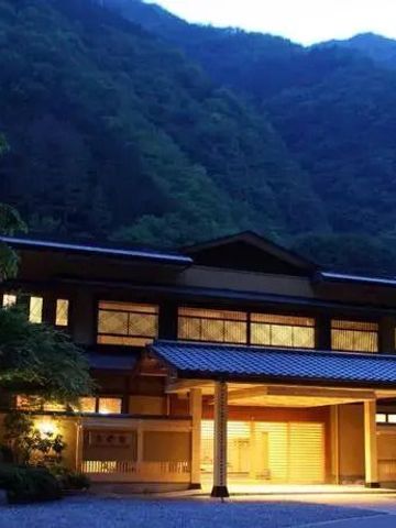 Abendaufnahme des Nishiyama Onsen Keiunkan umgeben von bewaldeten Bergen