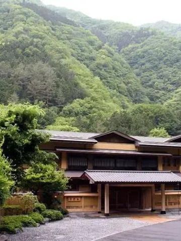 Tagesaufnahme des Nishiyama Onsen Keiunkan eingebettet in grüne Hügel