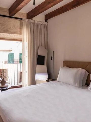 Modernes Hotelzimmer mit Holzbalkendecke und Zugang zu einem kleinen Balkon.