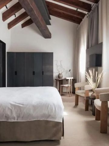 Geräumiges Hotelzimmer mit gemütlicher Sitzecke und rustikaler Holzbalkendecke.
