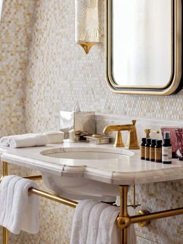Luxuriöser Waschtisch im Badezimmer mit goldenen Akzenten und Pflegeprodukten.