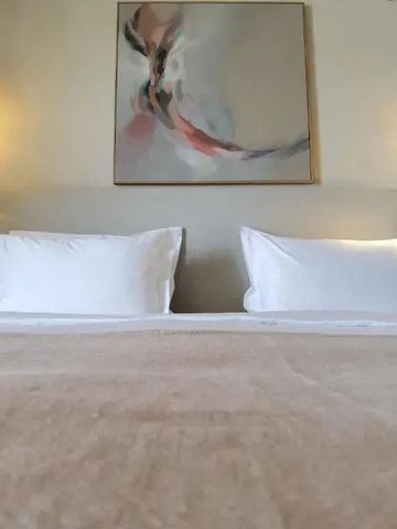 Einladendes Bett in neutralen Tönen mit moderner Kunst