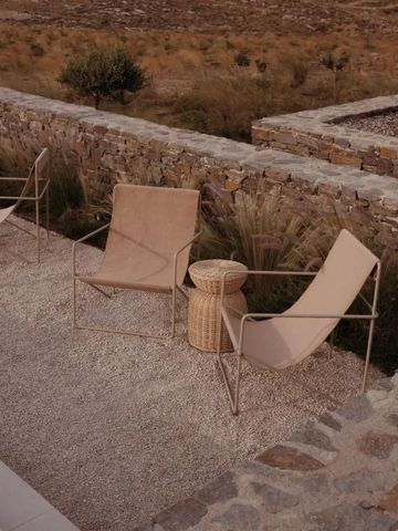 Moderne Outdoor-Sitzgelegenheiten auf Kieselboden vor einer Steinmauer.