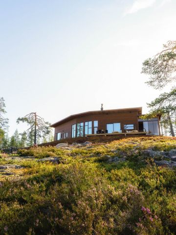Octola Villa auf einem Felsen zwischen Kiefern im Sommer, davor Heidekraut und Moos