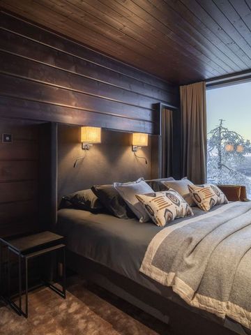 Hauptschlafzimmer der Octola Villa mit Doppelbett, Sessel und Panoramafenster zur Winterlandschaft