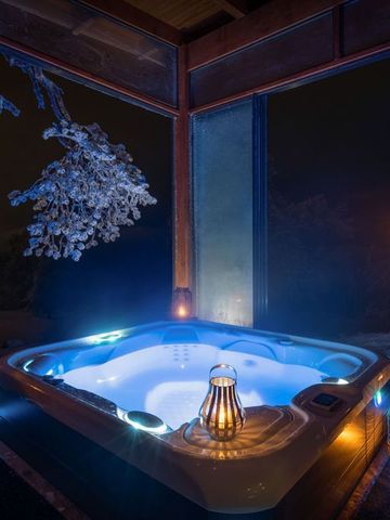 Beleuchteter Hot Tub auf der Terrasse der Octola Villa bei Nacht, umgeben von Laternen und Schnee