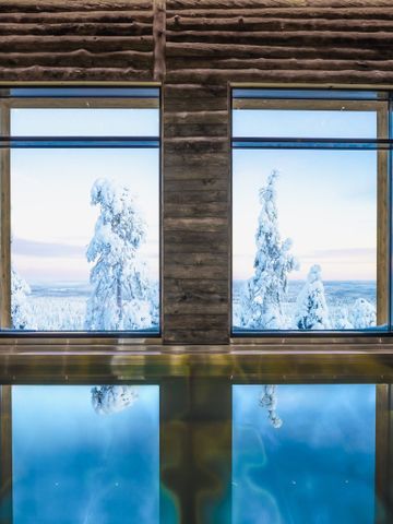 Innenpool im Spa von Octola mit Rundholzwänden und Fenstern zu verschneiten Bäumen