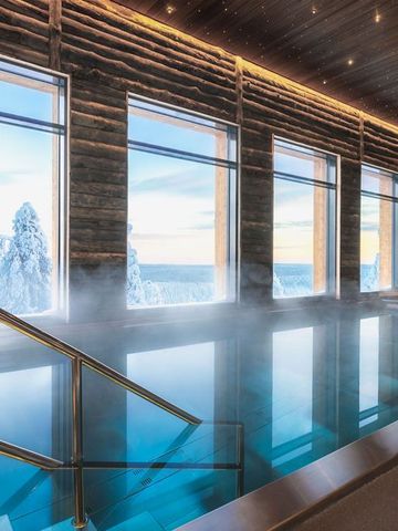 Innenpool im Spa von Octola mit Holzwänden und großen Fenstern zum verschneiten Wald