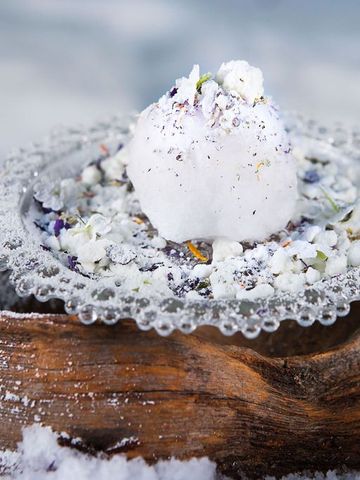 Dessert auf einem Glasteller, angerichtet auf einem Holzstück im Schnee