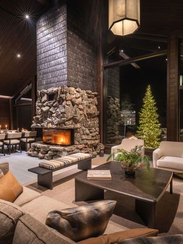 Lounge der Ultra Lodge mit Steinkamin, Sofas, Esstisch und Fenstern in die Winternacht