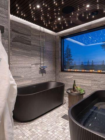 Spa-Bad mit zwei freistehenden Wannen, Bademänteln und Fenster zur Winterlandschaft